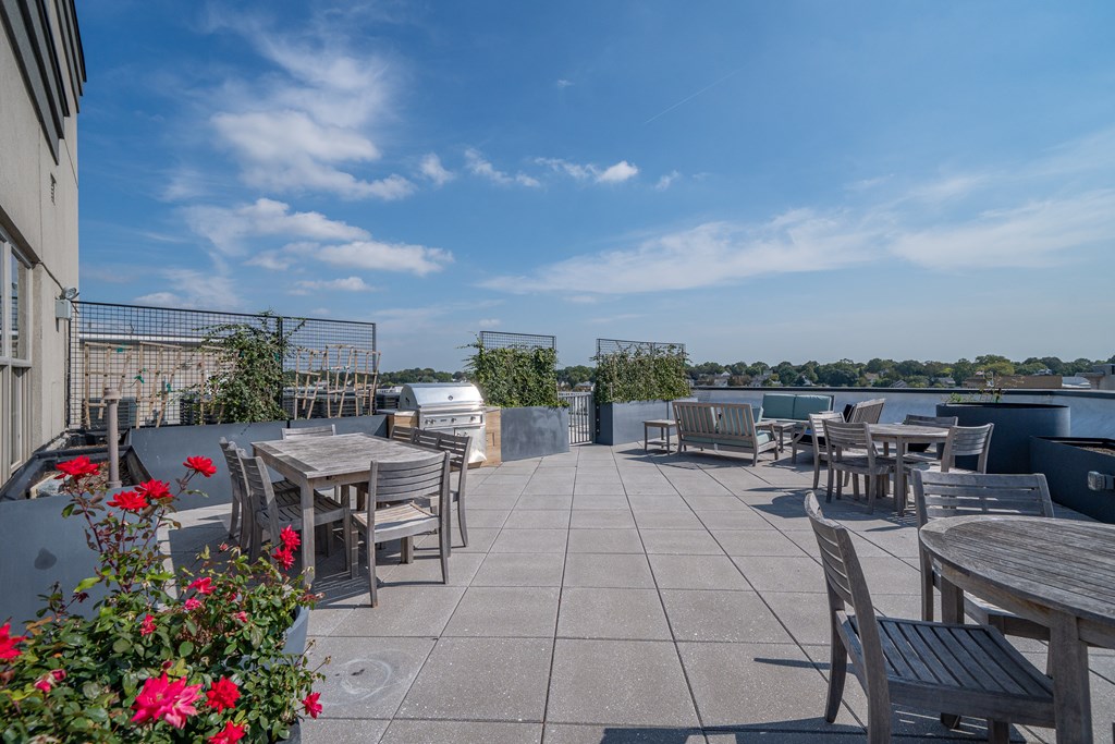 A patio with tables and chairs overlooking a body of water.
