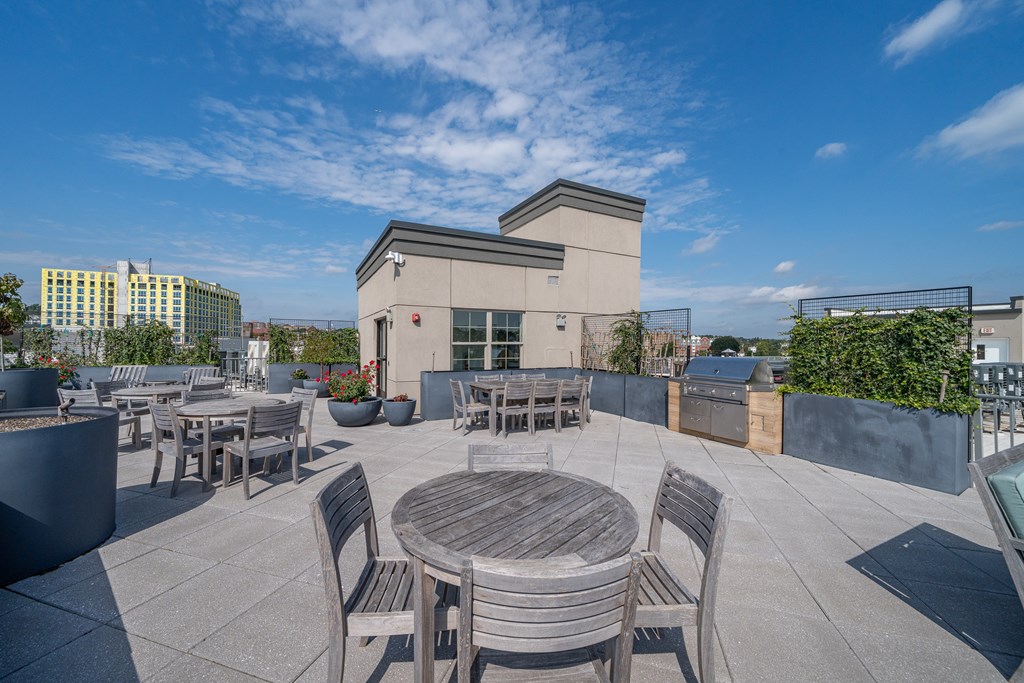 A patio with a table and chairs is surrounded by a fence and has a building in the background.