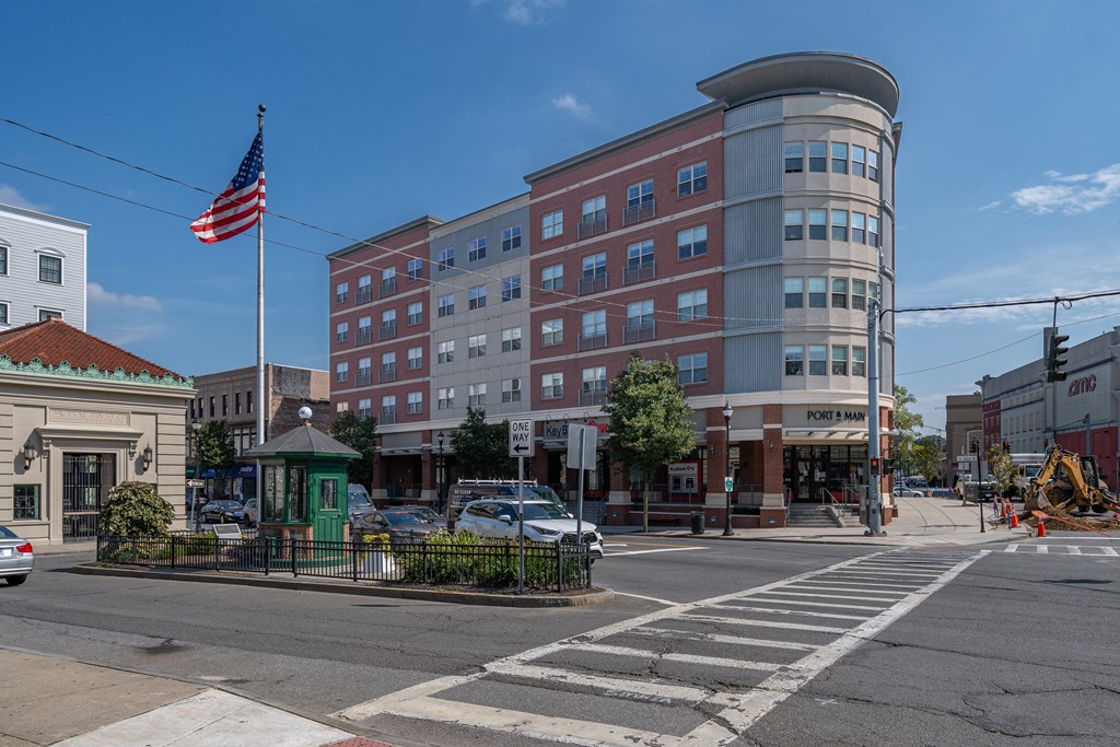 A street view with a building, cars, and a flag.