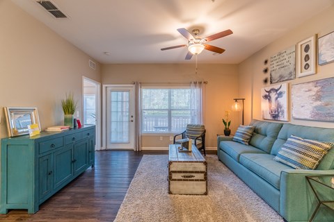A living room with a green couch and a wooden floor.