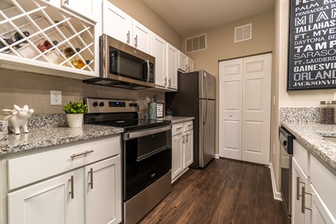 A kitchen with white cabinets and a black fridge.
