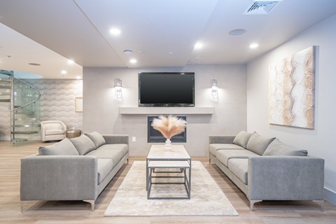 A modern living room with a grey sofa set and a flat screen TV mounted on the wall.