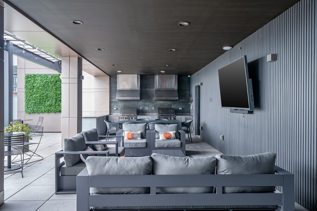 A modern living room with grey furniture and a flat screen TV mounted on the wall.
