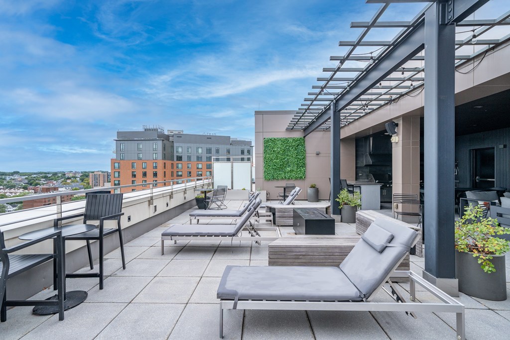 A rooftop patio with grey chairs and tables.