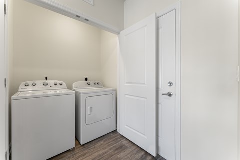 A white door is open to a laundry room with a washer and dryer.