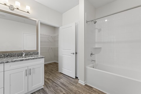 A white bathroom with a tub, sink, and mirror.