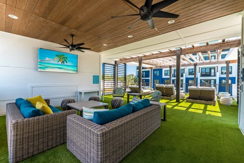 A living room with a ceiling fan and a painting of a beach scene on the wall.