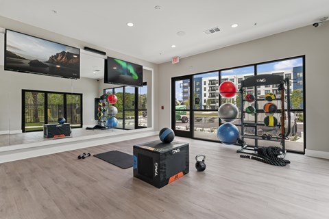 A gym with a variety of equipment including a box, kettlebell, and a pair of black flip flops on the floor.