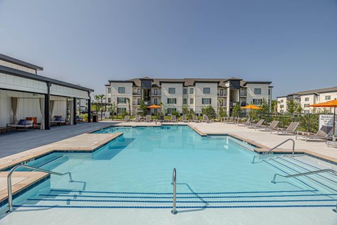 A large swimming pool in front of apartment buildings.