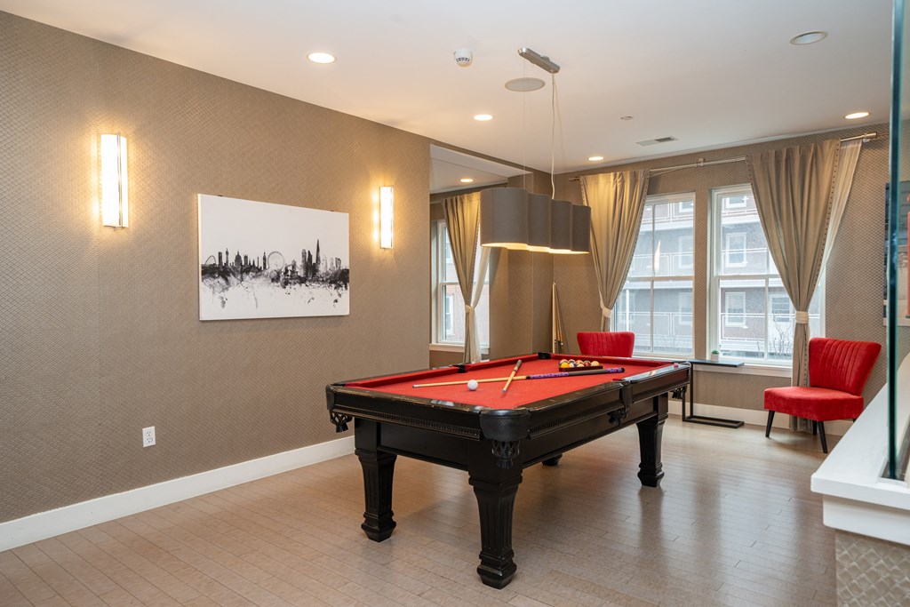a game room with a pool table and red chairs