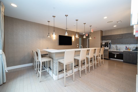 Community kitchen with bar seating and pendant lights at 750 Summer Street Apartments, Connecticut, 06901