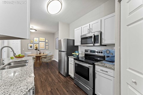 A kitchen with white cabinets and a wooden table.