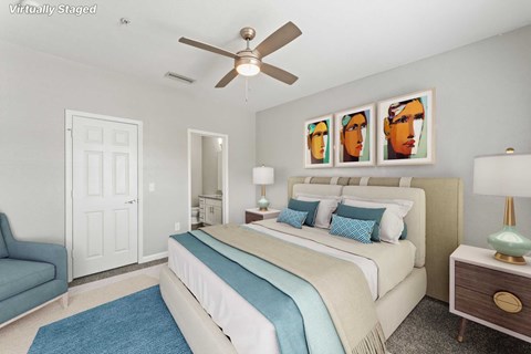 A bedroom with a bed, a couch, a ceiling fan, and a nightstand with a lamp.