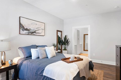 A bedroom with a large bed and a painting on the wall.