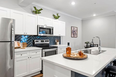 A kitchen with white cabinets and a white countertop with a tray of food on it.