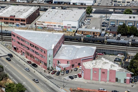 A train is on the tracks in front of a pink building.
