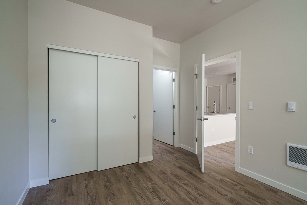 a bedroom with white walls and a door to a bathroom