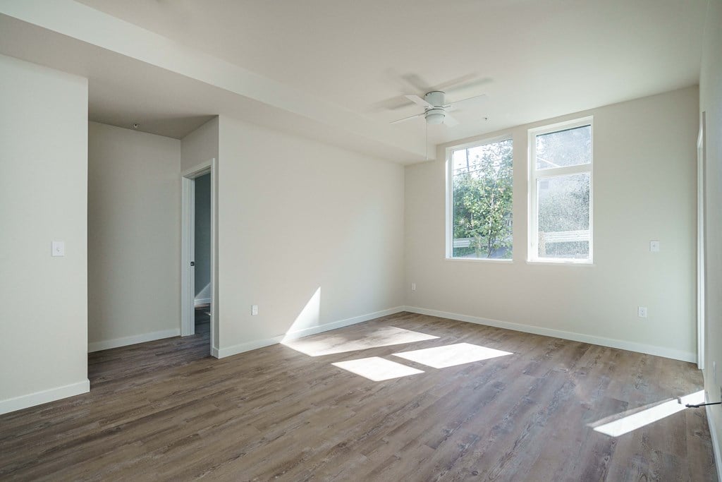 an empty living room with wood floors and a ceiling fan