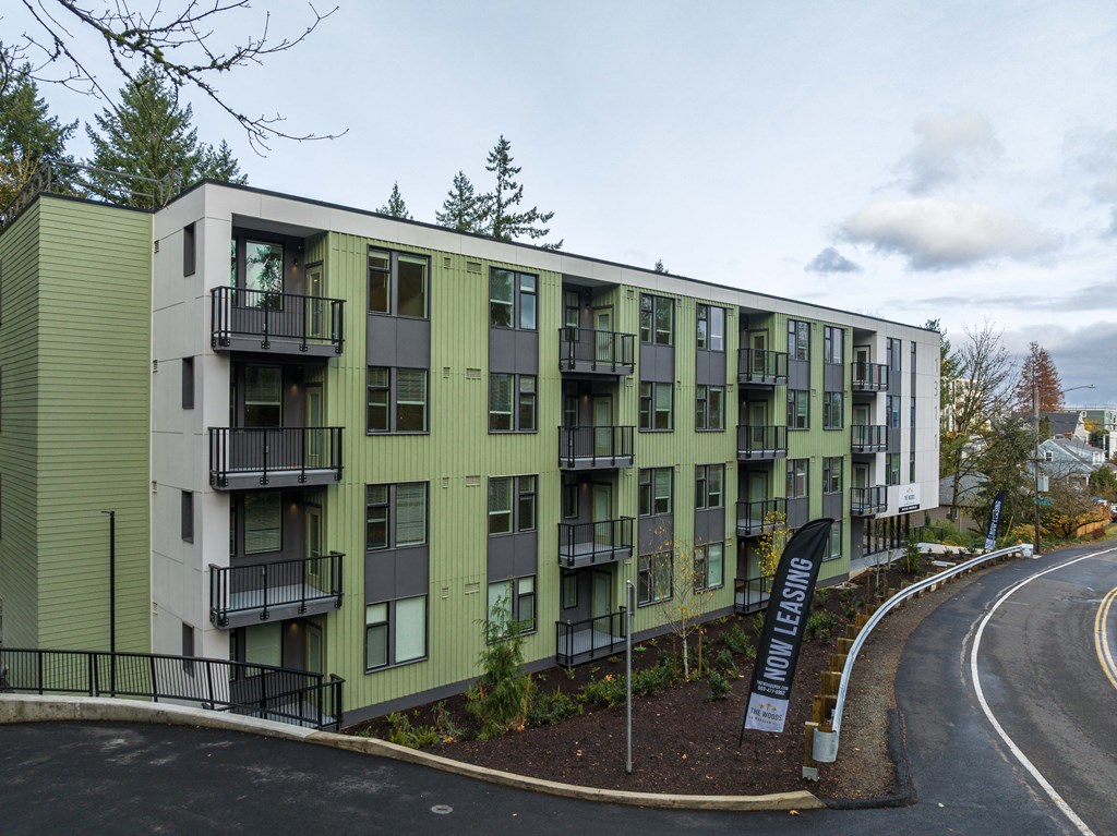 a green and white apartment building on the side of a road