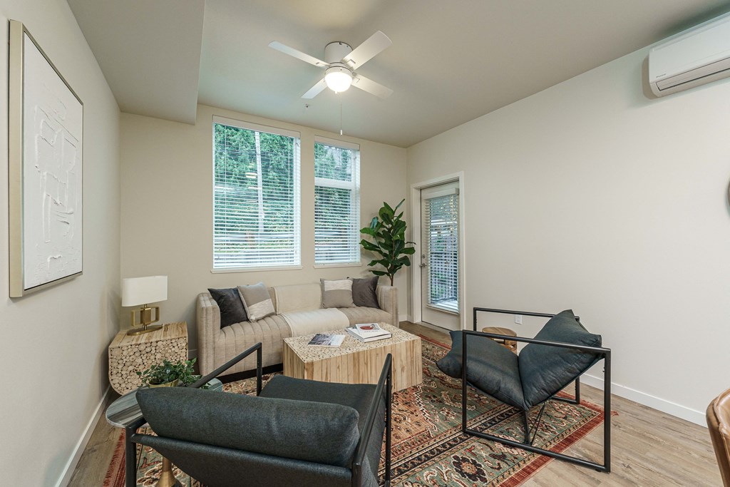 a living room with a couch and chairs and a ceiling fan