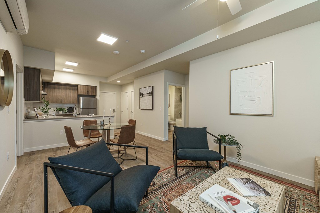 a living room and kitchen with chairs and a rug