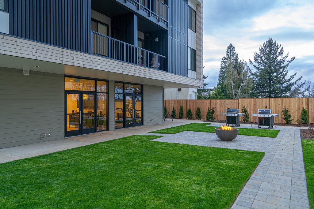 a backyard with a fire pit and a patio with two bbq pits