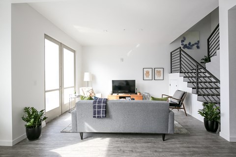 a living room with a gray couch and a staircase