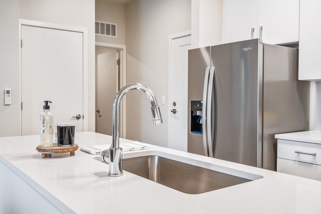 a kitchen with white countertops and a stainless steel refrigerator
