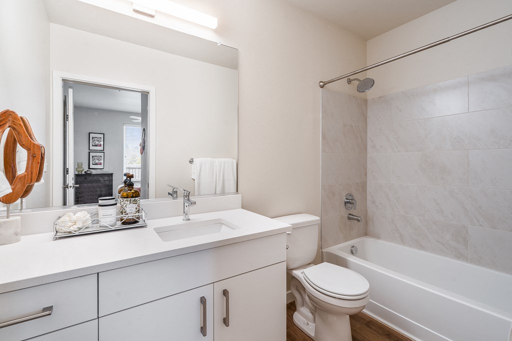 a bathroom with white cabinets and a white toilet next to a white bathtub