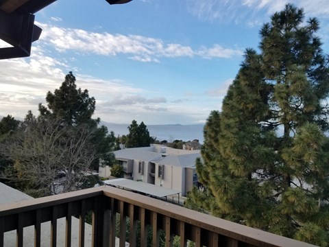 A house is seen from a balcony with trees in the foreground.