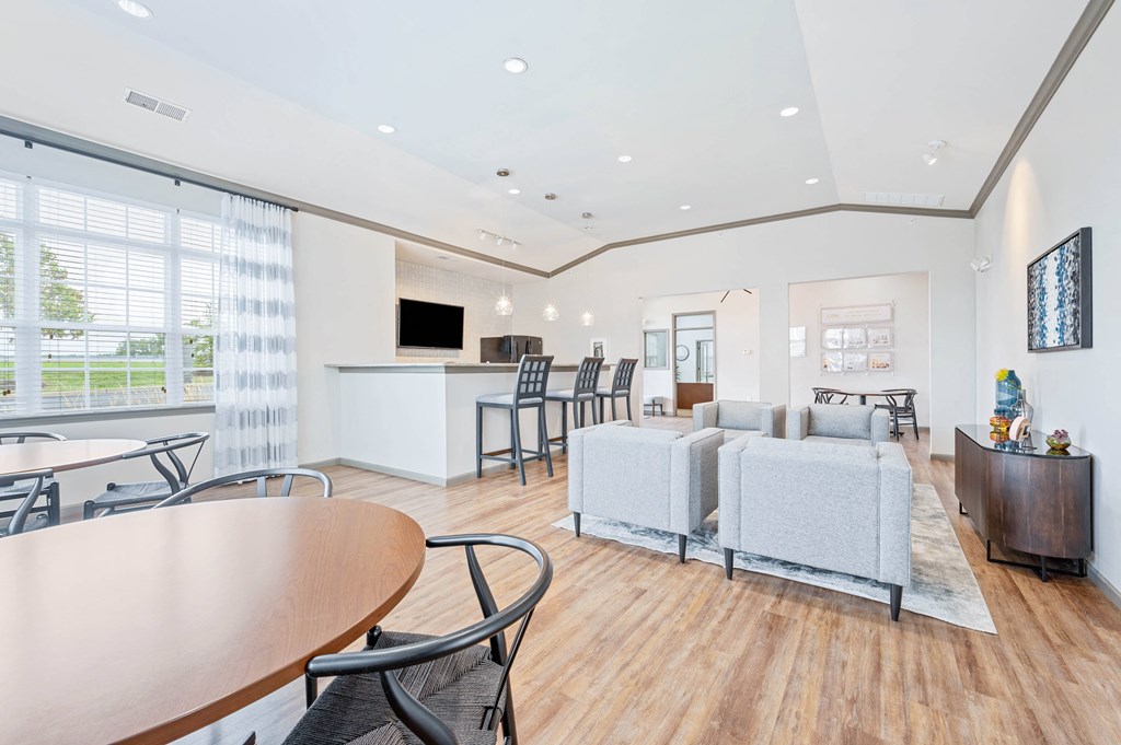 a resident clubhouse with couches tables and chairs and a kitchenette
