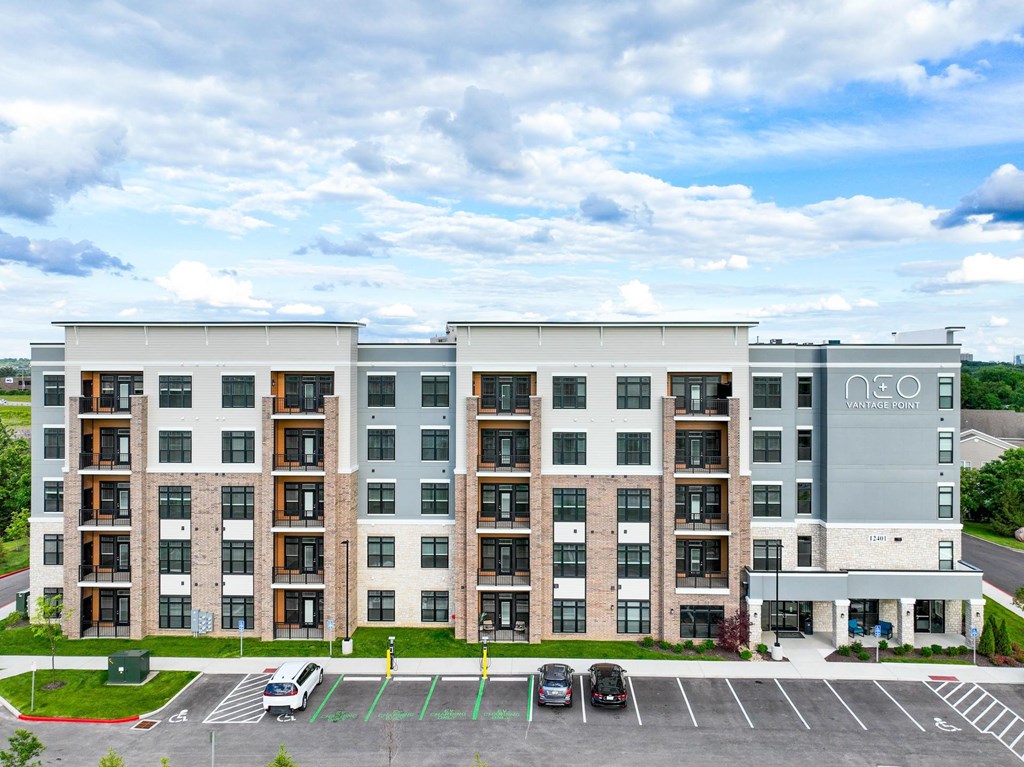 A large apartment building with a parking lot in front.