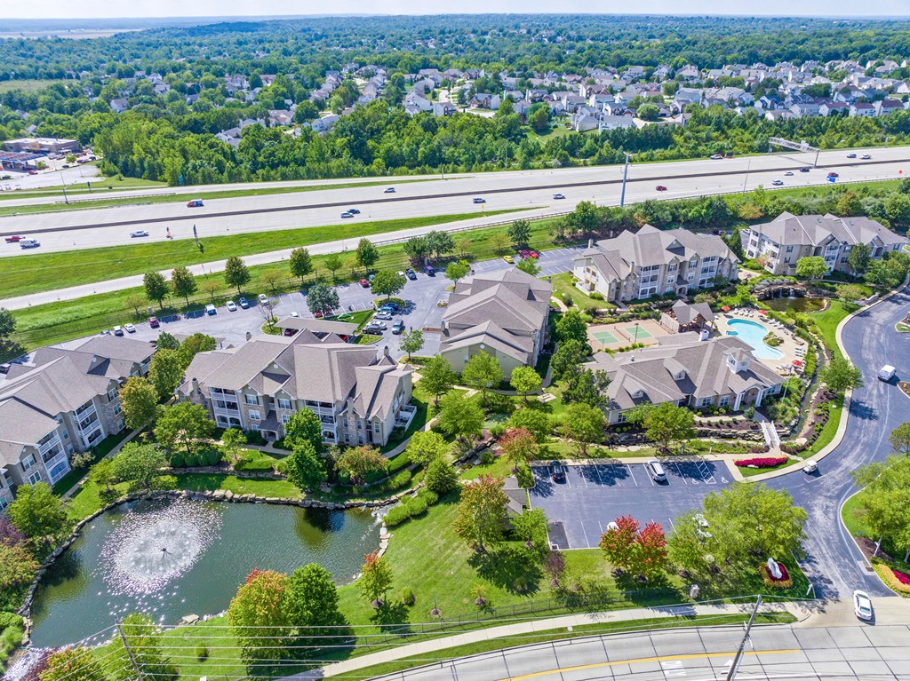 an aerial view of a large community with a lake and highway in the background