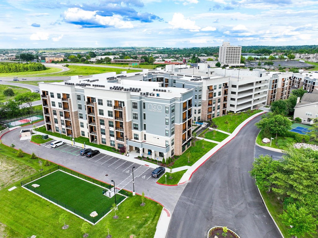 A large apartment complex with a green lawn and a playground.