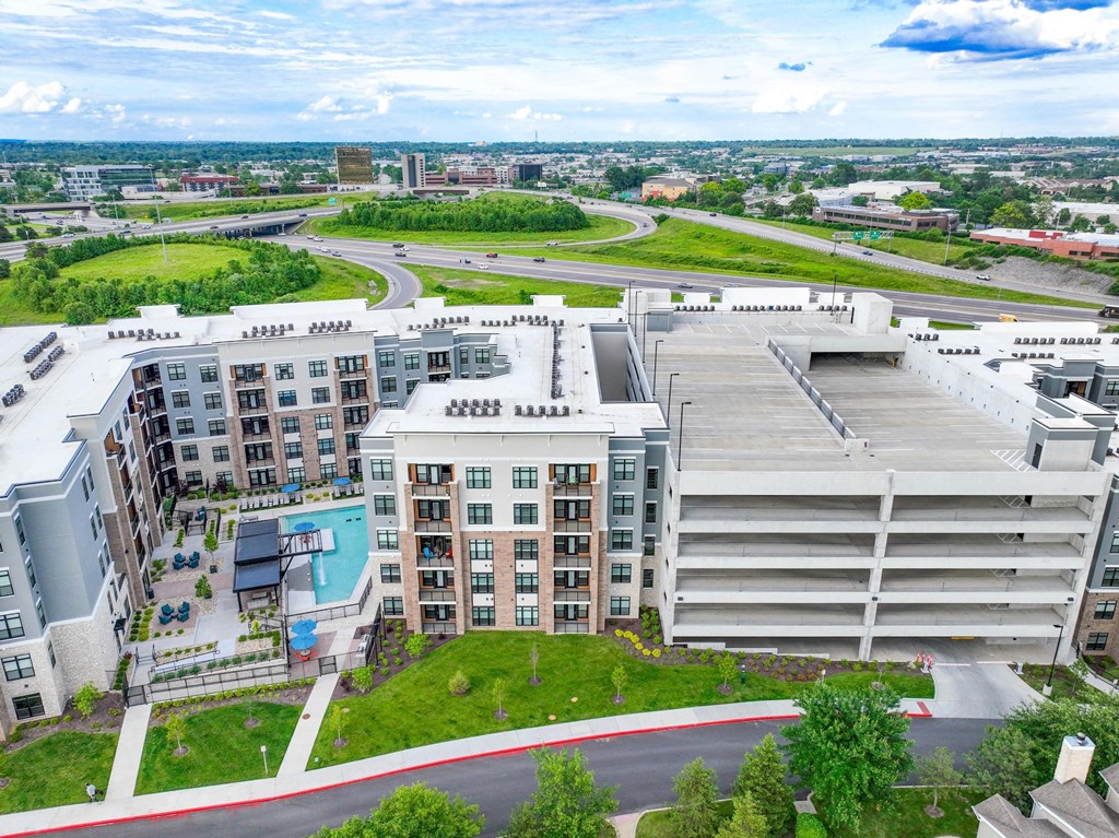 A large apartment complex with a pool and a parking garage.