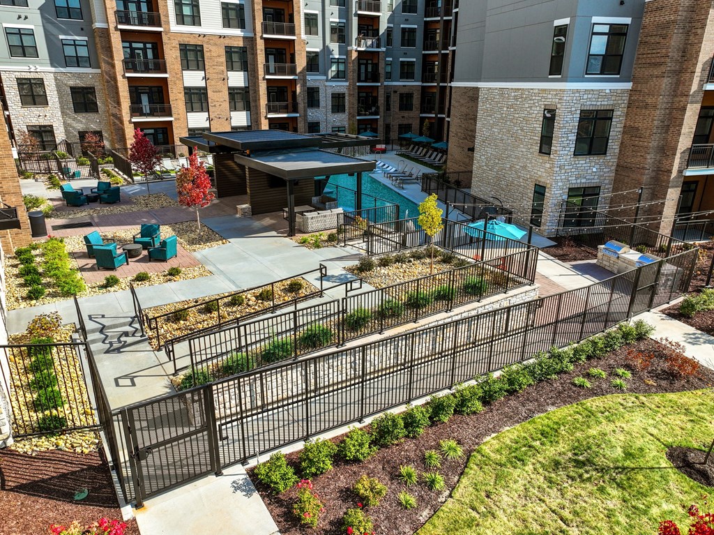 an aerial view of a courtyard with a fence and plants in front of a building