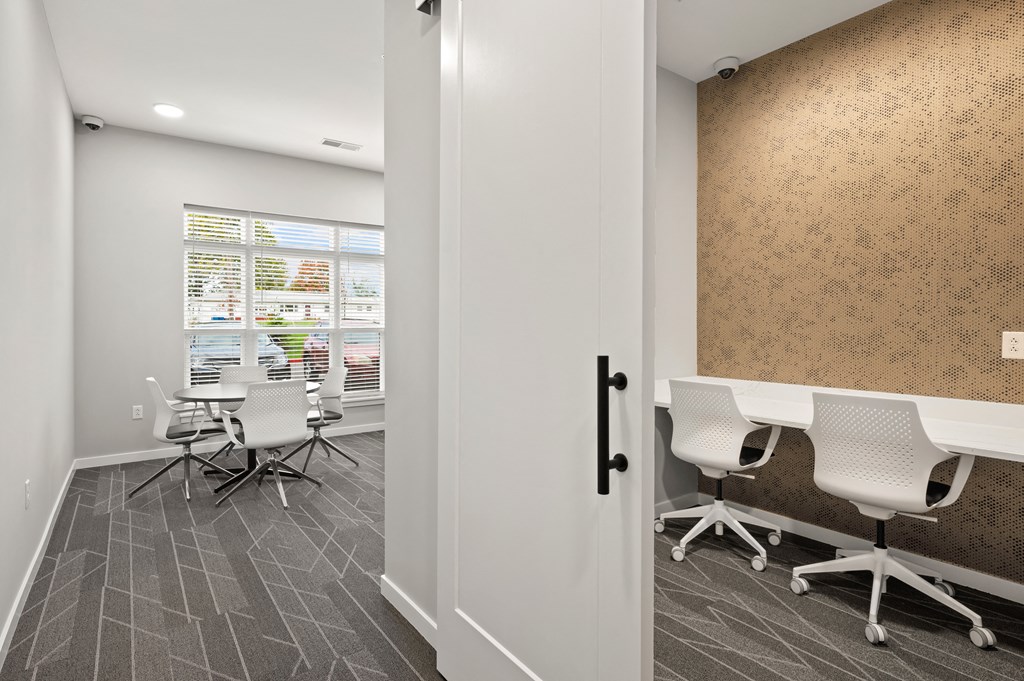 a conference room with white desks and chairs and a window