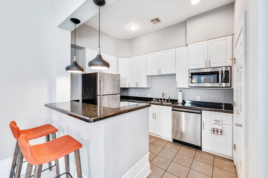 a kitchen with white cabinets and black countertops