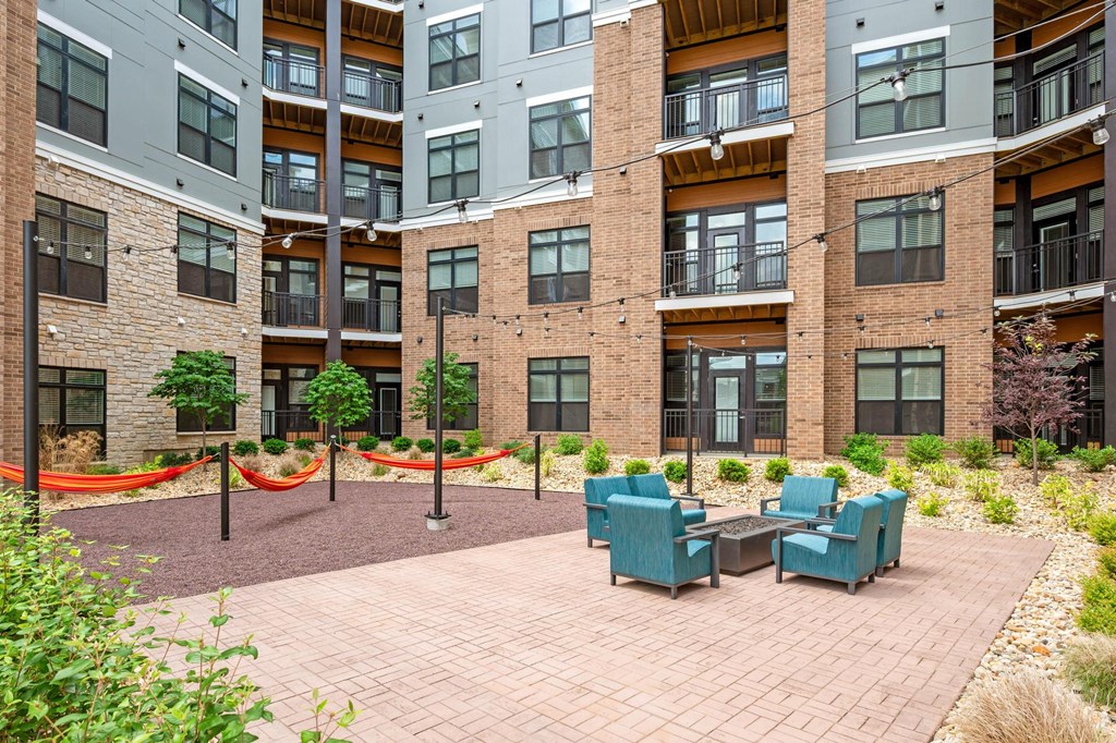 A courtyard with a brick floor and a table surrounded by chairs.