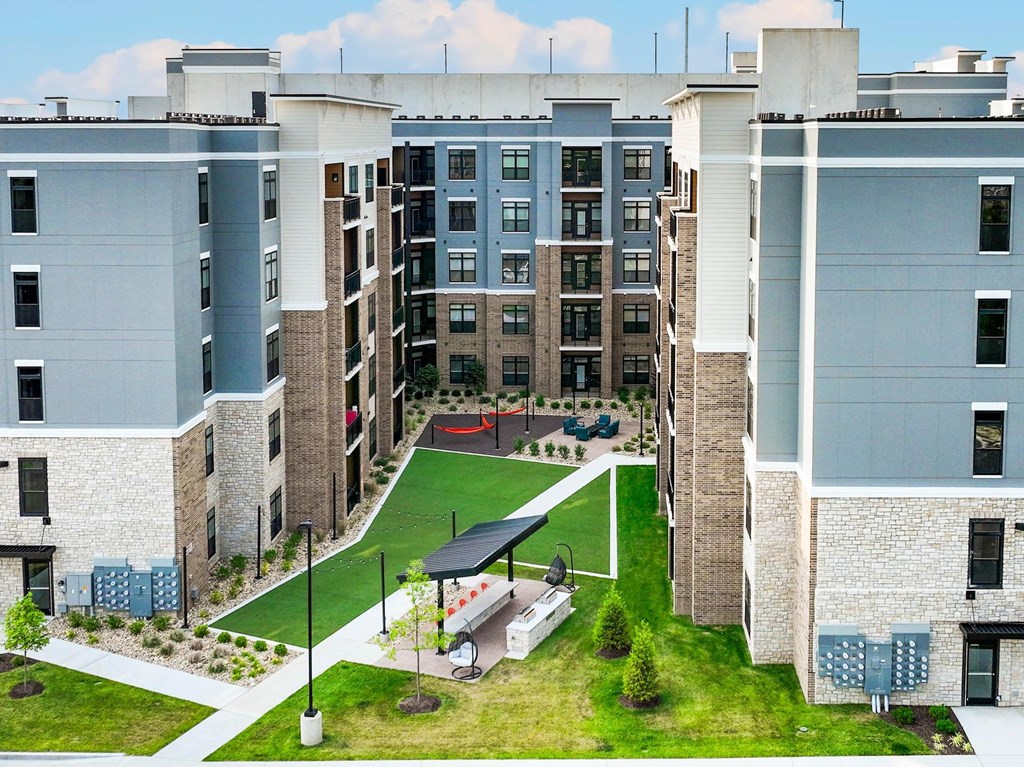 A large apartment complex with a green lawn in the middle.