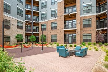 A courtyard with a brick floor and a small table surrounded by chairs.