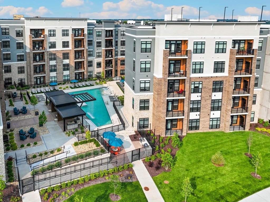 Apartment complex with a pool and a green lawn.