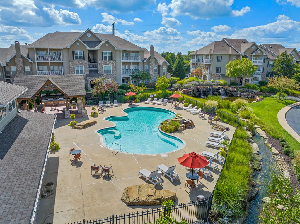 an aerial view of the resort style pool with lounge chairs and umbrellas