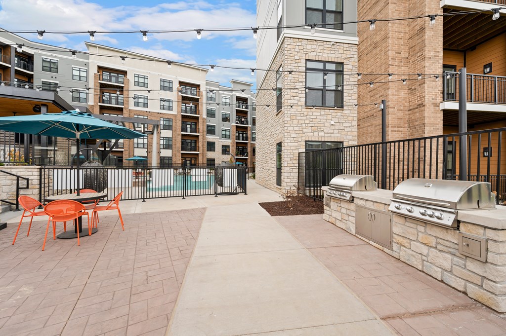 our patio has a grill and a table with chairs and an umbrella