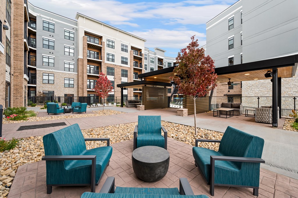 an outdoor lounge area with chairs and tables at an apartment complex