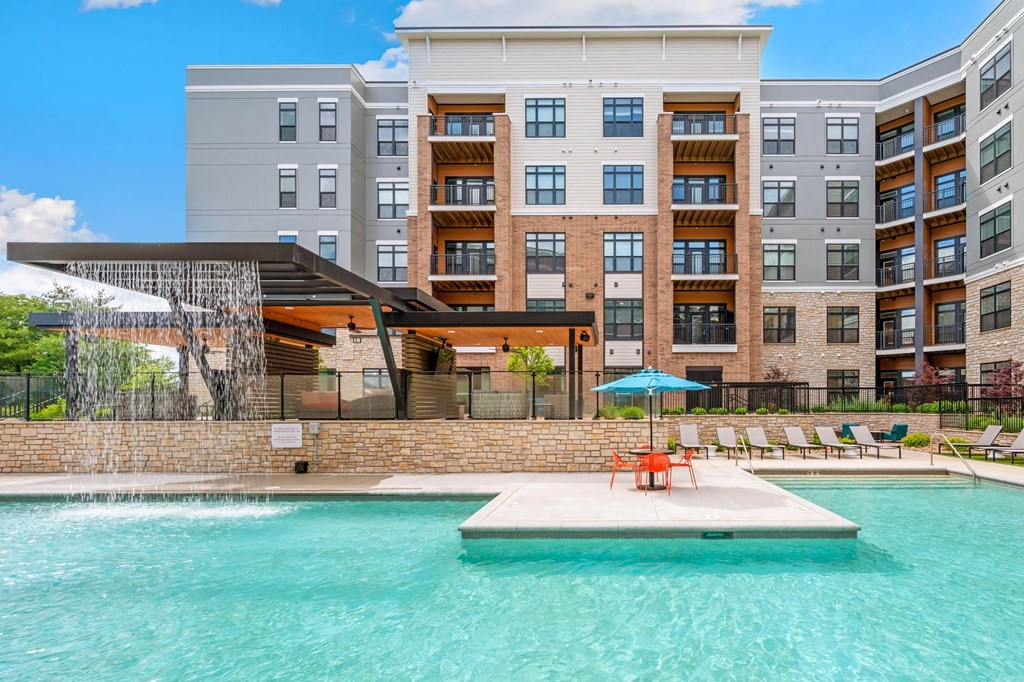 A large swimming pool in front of a multi-story apartment building.