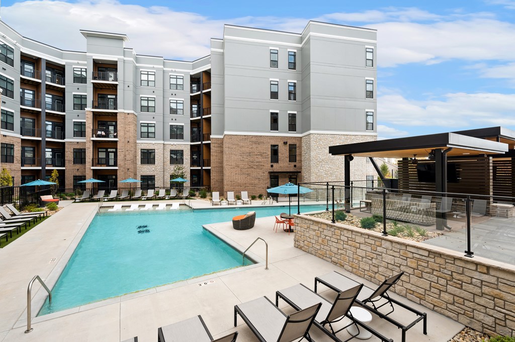 a swimming pool with chairs and an apartment building