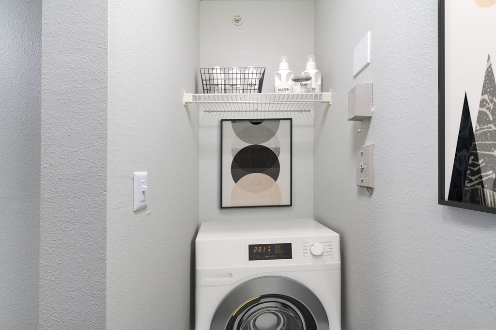 a white washer and dryer in a laundry room with a shelf above it