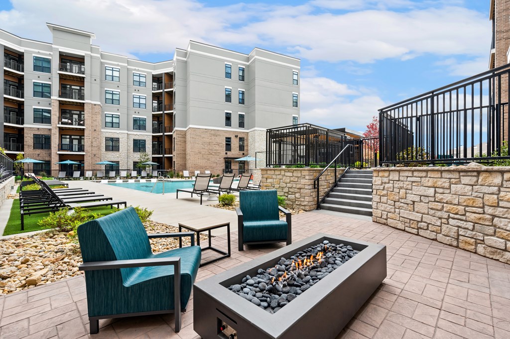 an outdoor patio with chairs and a fire pit and an apartment building