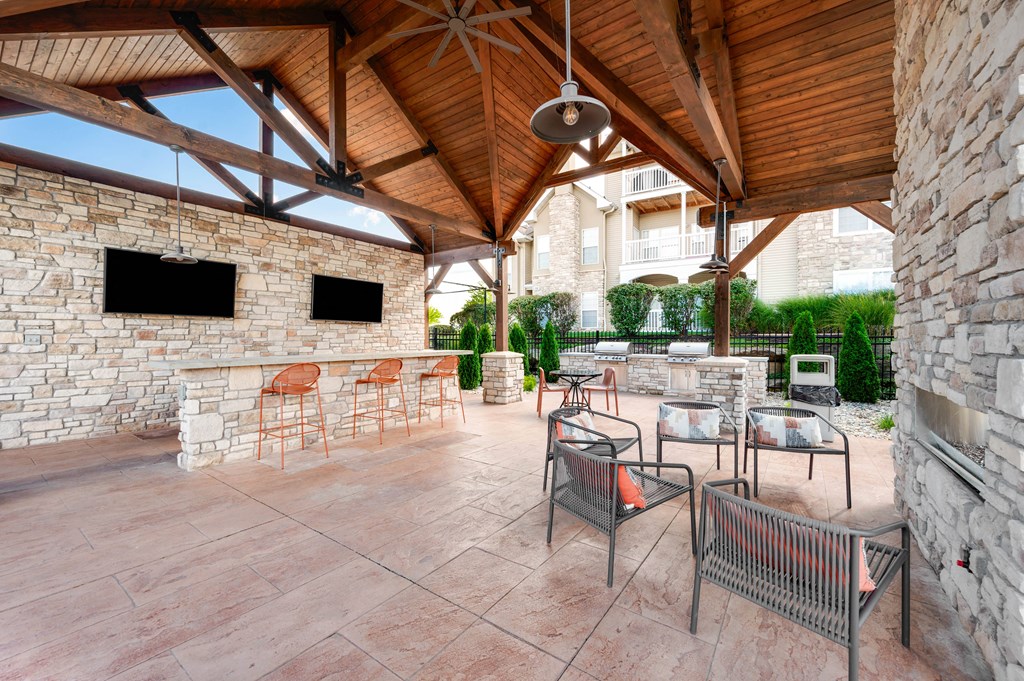 a covered patio with a fireplace and bar